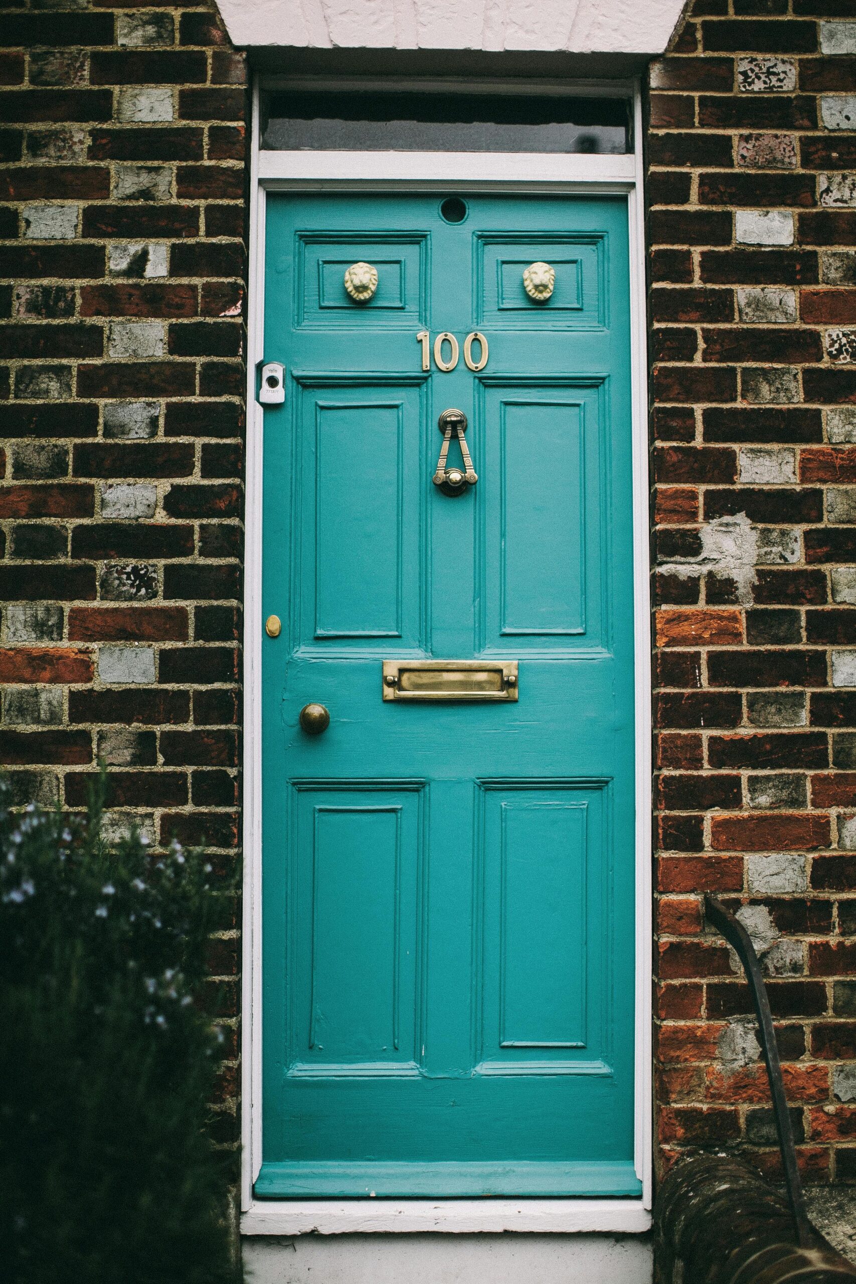 Charming teal wooden door on a classic red brick facade in Oxford, England.